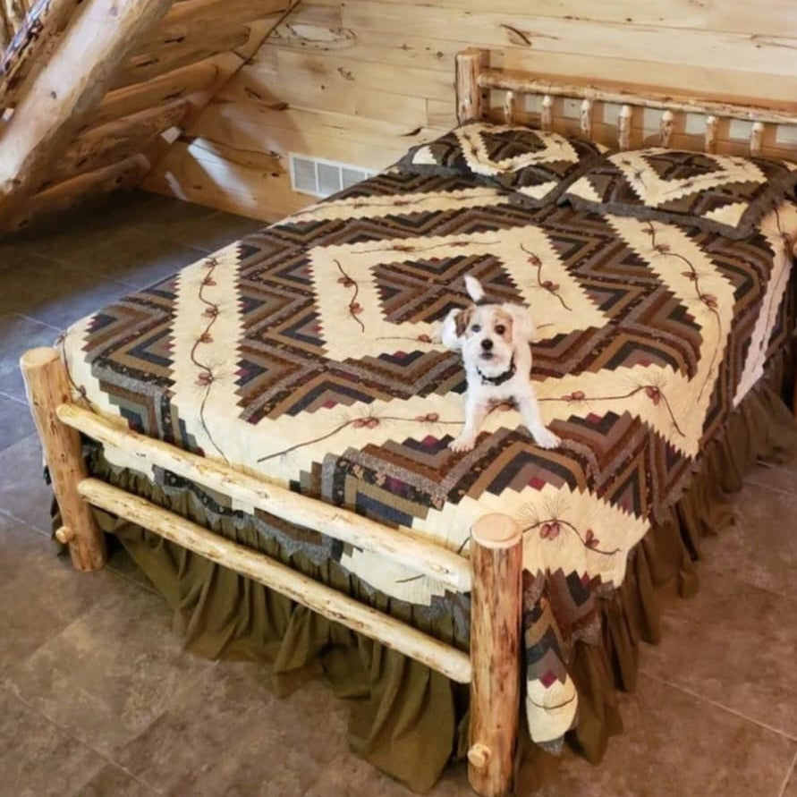 Dog standing on a log bed with a patterned quilt in a rustic cabin setting.