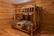Classic log bunk bed in a cozy cabin-style bedroom with wildlife-themed bedding